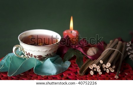 hot cup of tea with candle and sticks
