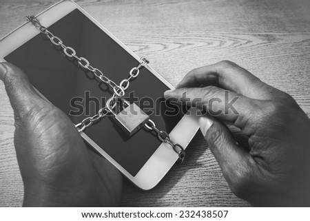 hand\'s man hold and touch on smart phone with chain lock ,black and white color tone. abstract background for solution to security smart phone form not owner.