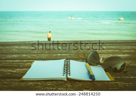 love summer decorate with eyeglasses and  note book on wooden floor on the blue sea.