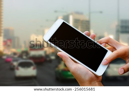 woman hand hold and touch screen smart phone, tablet,cellphone on city traffic in morning background.