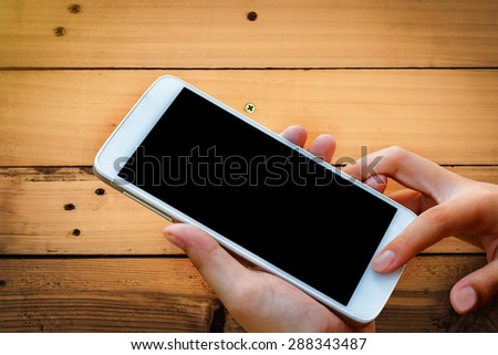 woman hand hold and touch screen smart phone,tablet,cellphone on wood texture , abstract background for mobile banking,online banking concept.