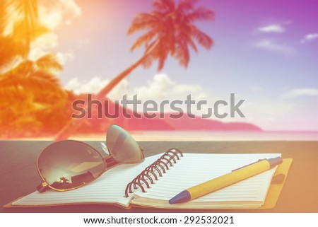 love summer decorate with eyeglasses and note book on wooden floor on tropical beach party on day noon light background,vintage filter color tone.