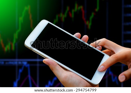 business woman hand hold and touch screen on smart phone,tablet,cellphone over blur  stock chart market background,with filtered red and green color,abstract background to forex and stock concept.