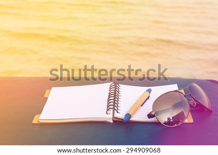 love summer decorate with eyeglasses and note book on wooden floor on the blue sea,vintage color tone.