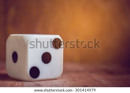 one old dice on wooden table,vintage color tone,abstract background to risk management concept.