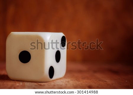 one old dice on wooden table,vintage color tone,abstract background to risk management concept.