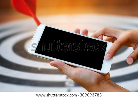 woman hand hold and touch screen smart phone,tablet,cellphone over blurred dart arrow target background , abstract background for mobile banking,online banking concept.