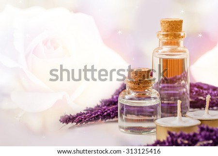 bottle of aroma essential oil with candle over blurred rose background, spa concept.