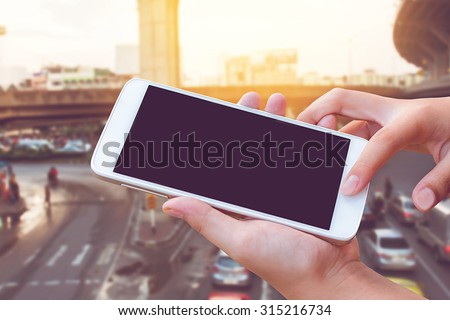 woman hand hold and touch screen smart phone, tablet,cellphone on city traffic accident in morning background,vintage filter color.