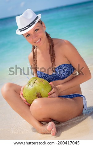 Beautiful young woman enjoying a cocktail in tropical paradise