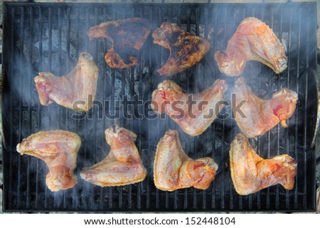 Fresh chicken wings on the grill, barely visible through the smoke.