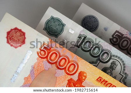 Russian banknotes 5000, 1000 and 500 rubles close up. Bright expressive illustration about economy and money of Russia. Nearest bill is highlighted in vivid color, other notes are pale. Macro
