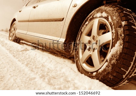 Close up of a cars tires on a snowy road - sepia tone