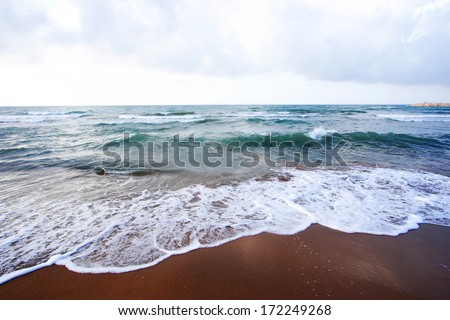 Beach pebbles under clear water with waves