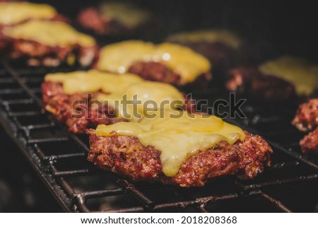 Burgers on the grill with gorm cheese melting on top of the meat. Meat cooked on the grill and charcoal. Heat on meat for cooking. Grilled meat for burger. Pork sandwiches. Cooking pork. Food.