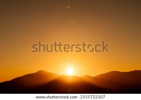 Similar – Image, Stock Photo Behind the hill with plants, a bright glow appears against the already darkened sky. The sun sets on the horizon.