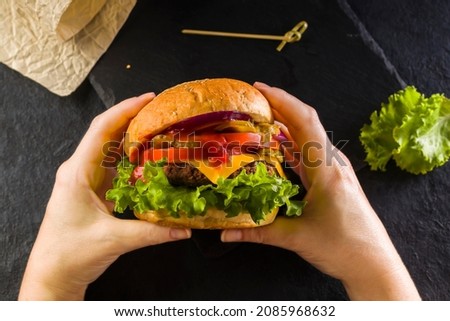 Similar – Image, Stock Photo Hands holding a cheeseburger with lettuce and tomato