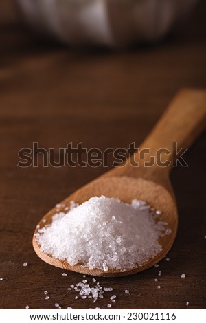 Sea salt in a bamboo spoon on wooden table
