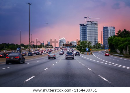 Night traffic. Cars on highway road at sunset evening in typical busy american city. Beautiful amazing night urban view with red, yellow and blue sky clouds. Sundown in downtown. Сток-фото © 