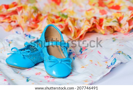 Pair of blue child`s shoes on red and yellow dress with chiffon. Dancing, hobby, free time concept. Selective focus.