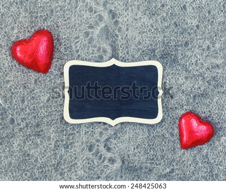Closeup macro texture of knitted wool grey shawl with two red hearts and wooden plate board plaque with copy space for text, Valentine holiday card, love retro vintage concept
