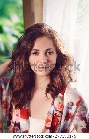 Portrait of beautiful innocent Caucasian adult girl woman with long dark red brown hair in white dress in park and shawl scarf outside on sunset sunrise morning