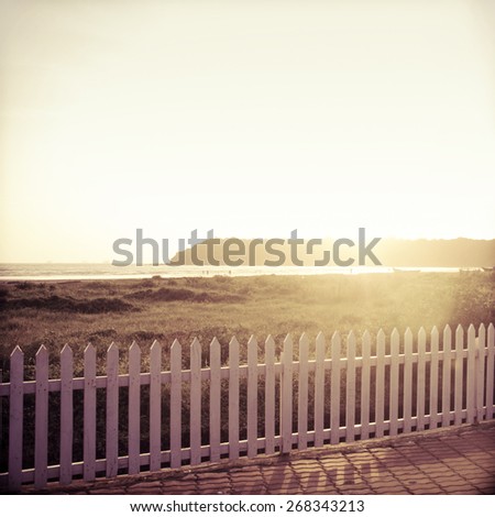 An wooden fence at the beach side. Sun rising from the hill. Vintage image.