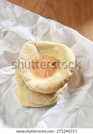 Heap of arabic Pita breads placed on wrinkled paper.