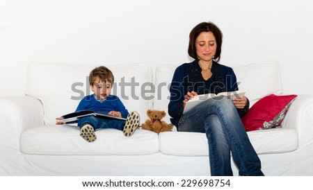 Mother and son on the couch reading a book with a red pillow, each reading a different book