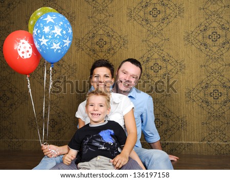 Beautiful family portrait sitting on the floor with colored balloons.
