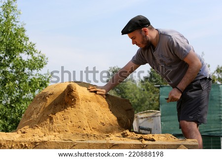 Sofia, Bulgaria - August 24, 2013: A young man is making a bear head out of sand participating in an annual Sand Sculpture Festival in Sofia.