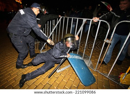 Sofia, Bulgaria - November 12, 2013: A policeman is falling near a fence while people are protesting against the Bulgarian government in the center of country\'s capital Sofia.