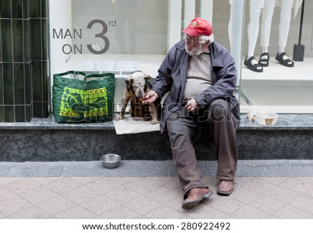 Budapest, Hungary - April 30, 2015: An old man is begging in front of a fashion shop in a main street in Budapest, Hungary.