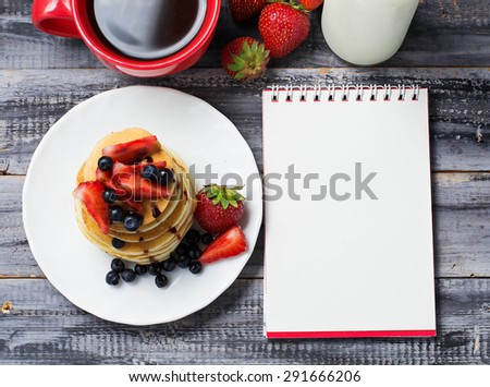 Breakfast with pancakes, coffee, milk and open notebook. Selective focus, top view