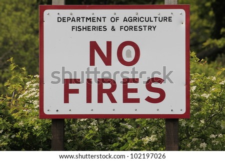 Bold red lettered \'No Fires\' sign on a white background in the countryside