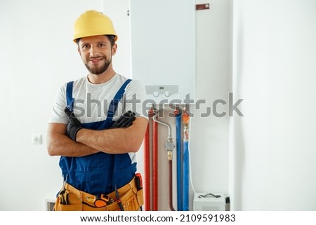 Smiling technician servicing the house heating system looking at camera while standing with arms crossed Photo stock © 