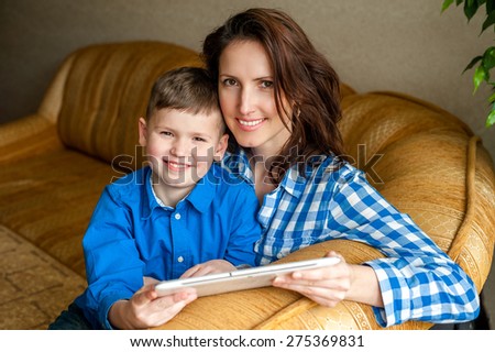 Smiling mother and son using digital tablet, look ahead at a screen with great interest. Technology to stimulate a thriving mind.
