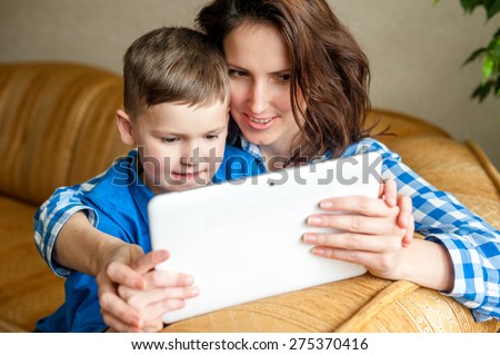 Smiling mother and son using digital tablet, look at a screen with great interest. Technology to stimulate a thriving mind.