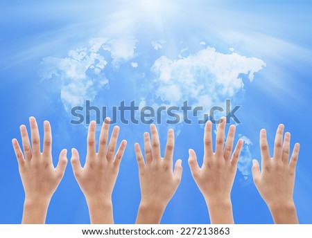 People raising hands on world map of clouds background