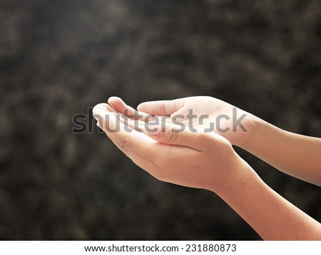 Human open hands with palms up over blurred soil background