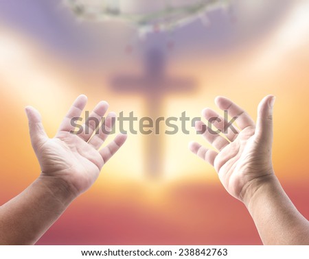Human open empty hands with palms up, over blurred crown of thorns and the cross on a sunset.
