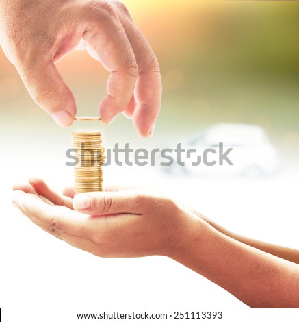 Human hand adding a golden coin in golden coins on another hands over white car on sunset background. Concept for money coin, insurance, buying, renting, repair, fuel , service.