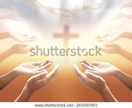 Human hands praying over blurred crown of thorns and the cross on a sunset.