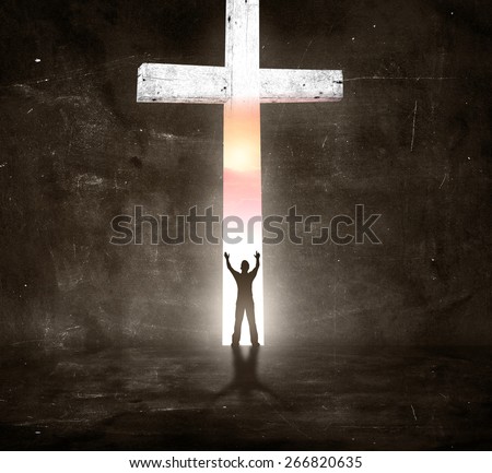 Sepia tone. Silhouette human raising hands over the white cross in dark room and looking to view of sunset.