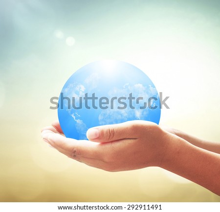 Vintage style. Human hands holding blue planet on blurred abstract beautiful sea or ocean or forest or desert over colorful sunset background. Ecology concept. World Environment Day concept.