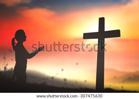Silhouette woman praying over the cross on beautiful sunset with amazing light background.