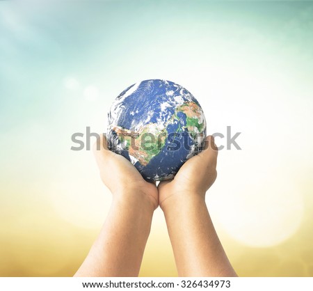 Planet in human hands on blurred beautiful nature background. Environment concept. Elements of this image furnished by NASA.