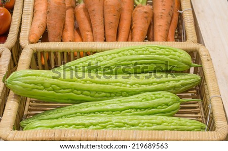 bitter melon  and carrots harvested products on wooden basket