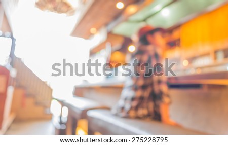 blur image of Young slim girl sits on a high bar stool in cafe.