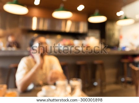 blur image of woman use mobile phone in coffee shop for background usage(vintage color tone)